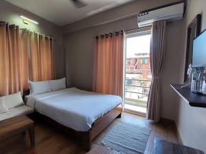 a hotel room with a bed and a window at Hotel Blossom in Pokhara