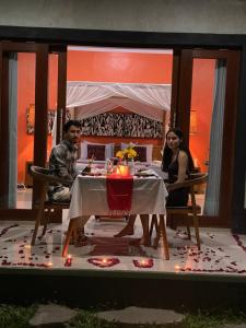 Ubud mesari Private Pool Villa في أوبود: يجلس رجل وامرأة على طاولة مع أضواء