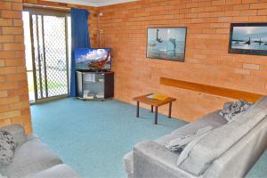 a living room with two couches and a brick wall at Cameo Court 2 in South West Rocks