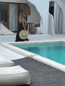 a woman wearing a hat standing next to a swimming pool at Sal Central in Uluwatu