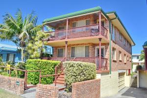 a brick house with a balcony and bushes at Carrington 6 in South West Rocks