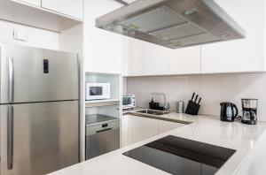 eine Küche mit weißen Schränken und einem Edelstahlkühlschrank in der Unterkunft 72 floor 2BR at the Address JBR with Marina Views! in Dubai