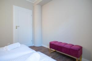 sypialnia z fioletową ławką przed łóżkiem w obiekcie Apartamenty Na Szlaku, MyWeek w Kłodzku