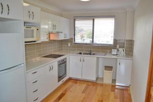 a kitchen with white cabinets and a white refrigerator at Woody Wonder in South West Rocks