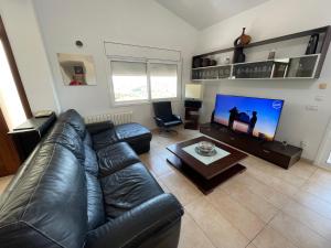 a living room with a leather couch and a flat screen tv at Villa for 2 families in Blanes