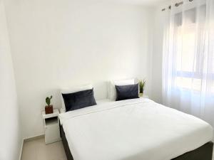 białe łóżko w białym pokoju z oknem w obiekcie Melony Apartments Yam Suf Street w Ejlat