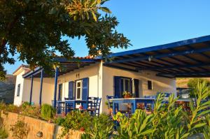 a house with blue chairs in front of it at Sunset Hotel in Agios Ioannis Kaspaka