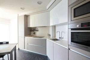cocina blanca con fregadero y microondas en Apartamento Singular Deluxe, en Pamplona
