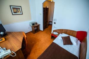 1 dormitorio con 1 cama y escritorio con TV en Emerald Boutique Hotel, en Târgu Mureș