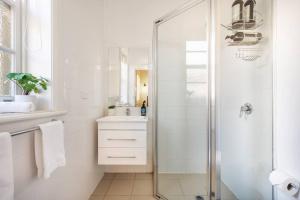 a white bathroom with a shower and a sink at 'Micah House' A Central Mudgee Art Deco Hideaway in Mudgee +35 photos