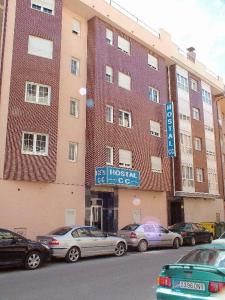 a large brick building with cars parked in front of it at Hostal CC in Aranda de Duero