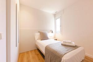a small white bedroom with a bed and a window at Bravissimo Sirenes, 2-bedroom apartment in Girona