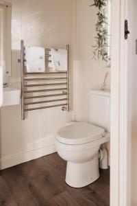 a white bathroom with a toilet and a towel rack at The Dragonfly Shepherds Hut in Colchester