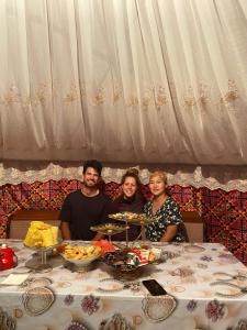 Un groupe de personnes assises à une table avec de la nourriture dans l'établissement Guesthouse Damira, à Kyzyloy