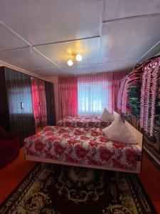 - une chambre avec un lit rouge et des rideaux roses dans l'établissement Guesthouse Damira, à Kyzyloy