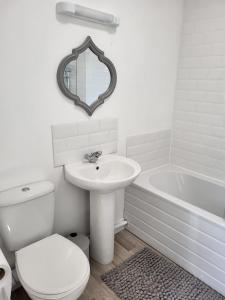 a white bathroom with a toilet and a sink and a tub at The Velvet Crab in Scarborough +11 photos