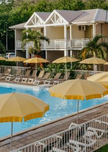 una piscina con sillas y sombrillas frente a un hotel en Hotel Le Recif, Ile de la Reunion en Saint-Gilles-les-Bains