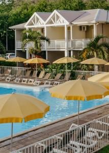 a pool with chairs and umbrellas in front of a hotel at Hotel Le Recif, Ile de la Reunion in Saint-Gilles-les-Bains