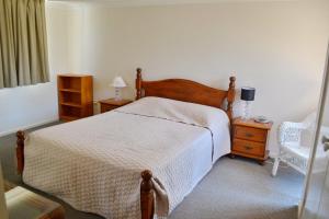 a bedroom with a bed and a chair and a table at Beach Retreat in South West Rocks