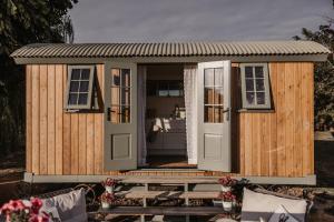 a wooden shed with a door and a bench at The Dragonfly Shepherds Hut in Colchester