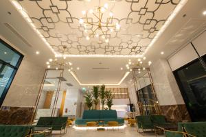 un vestíbulo con sillas verdes y una lámpara de araña en Pattaya Discovery Beach Hotel - SHA Extra Plus, en Pattaya central