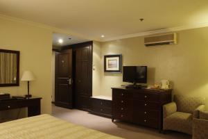 マニラにあるHerald Suites Solanaのベッドルーム(ベッド1台、テレビ、椅子付)