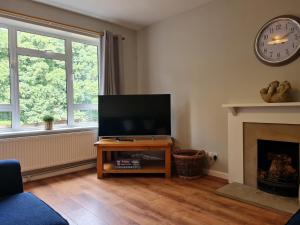 a living room with a flat screen tv and a fireplace at The Farmhouse - Linton Horseheath in Linton