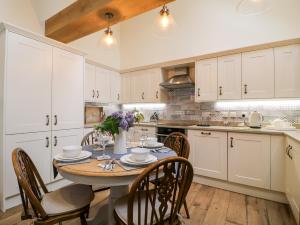 a kitchen with white cabinets and a table with chairs at Churn Dash Cottage in Denby