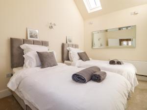 two large white beds in a room with a mirror at Churn Dash Cottage in Denby