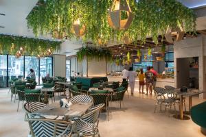 a restaurant with tables and chairs and people in the background at Pattaya Discovery Beach Hotel - SHA Extra Plus in Pattaya Central