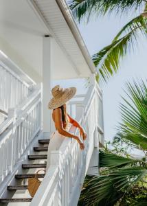 a woman in a straw hat standing on the stairs of a house at Hotel Le Recif, Ile de la Reunion in Saint-Gilles-les-Bains
