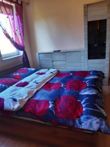 a bed with red flowers on it in a bedroom at Wczasy U Piotra in Grabno