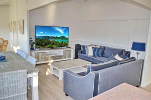 a living room with a couch and a tv at Joanna Cottage - Bring your own linen in South West Rocks