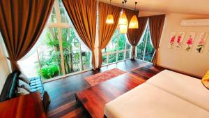 a living room with a couch and large windows at Rain Forest Resort in Ban Pak Yang