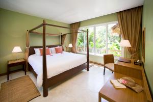 Centara Chaan Talay Resort And Villas Trat في Ban Khlong Muang: غرفة نوم مع سرير المظلة ومكتب وسيدكس السرير سيدكس