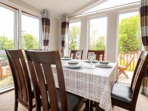 comedor con mesa, sillas y ventanas en 23 Bossiney Bay, en Tintagel