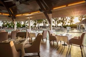 a restaurant with tables and chairs and a pool at LUX* Saint Gilles Resort in Saint-Gilles-les-Bains