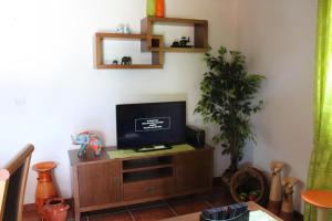 a living room with a flat screen tv on a cabinet at Zef's Cottage in São Vicente