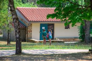 dwie kobiety stojące przed małym domem w obiekcie Village de gîtes de la Forêt de Ganigal w mieście Le Malzieu-Ville