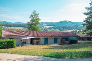 una casa con techo rojo en una colina en Village de gîtes de la Forêt de Ganigal en Le Malzieu-Ville