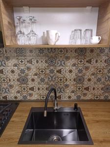 a kitchen with a sink and a tile wall at Cottage Toladi in Stepantsminda