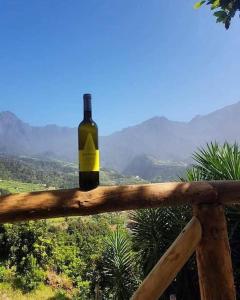 Una botella de vino encima de una barandilla de madera en Zef's chalet, en Senhora do Rosário