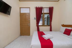 a bedroom with a bed with a red and white blanket at RedDoorz near RS Awal Bros Sudirman Pekanbaru in Parit