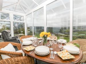 comedor con mesa, sillas y ventanas en Ty Twmp Tump Cottage, en Brecon