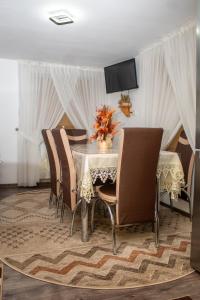 a dining room with a table with chairs and a television at Pensiunea Casa Ioana in Şugag