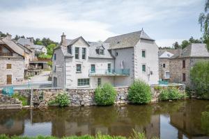 ein großes weißes Haus neben einem Fluss in der Unterkunft Résidence Les Rives Du Bès in Saint-Juéry