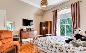 a bedroom with a bed and a chair and a window at Fountain Hill House in Derry Londonderry
