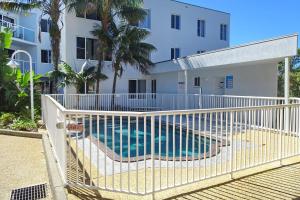 una valla blanca con piscina frente a un edificio en Ocean Shores Apartment 14 - Bring your own linen., en South West Rocks