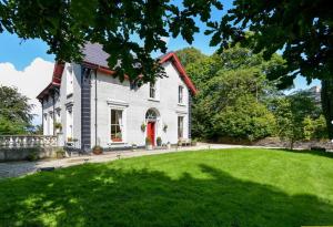 a white house with a red door and a yard at Fountain Hill House in Derry Londonderry