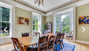 a dining room with a table and chairs and windows at Fountain Hill House in Derry Londonderry
